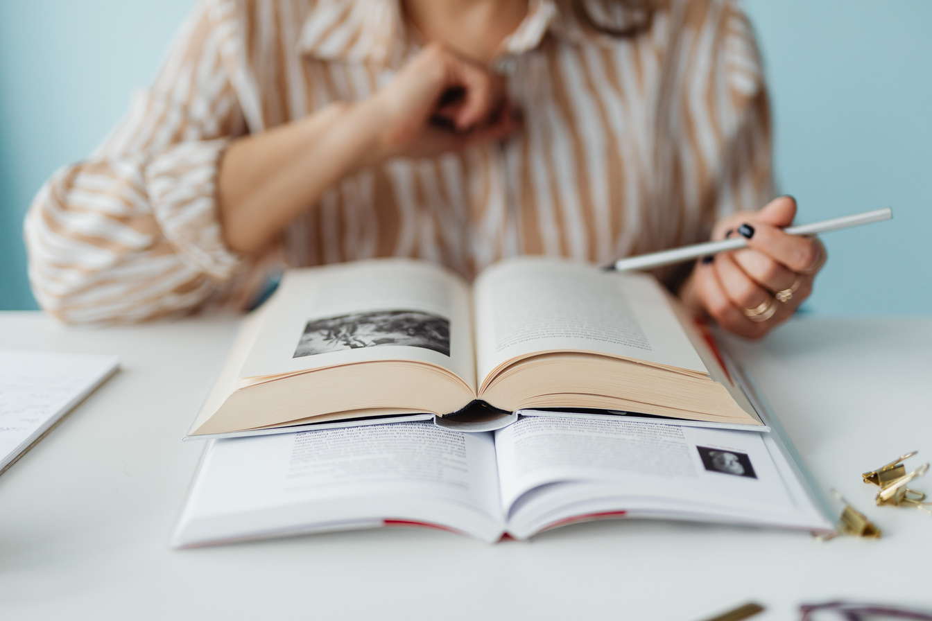 A Woman  Sitting at the Table Reading a Book